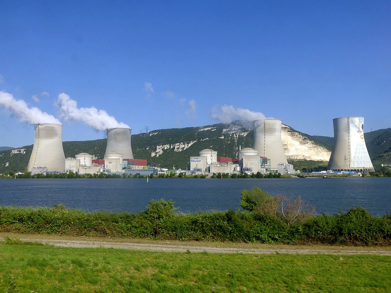 Cruas nuclear power plant beside the Rhône, with cooling towers and a river in the foreground.