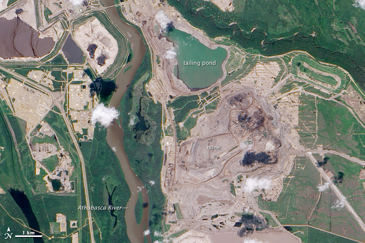 Satellite image of the Athabasca oil sands in Alberta, geometric pits cut into dark forest.