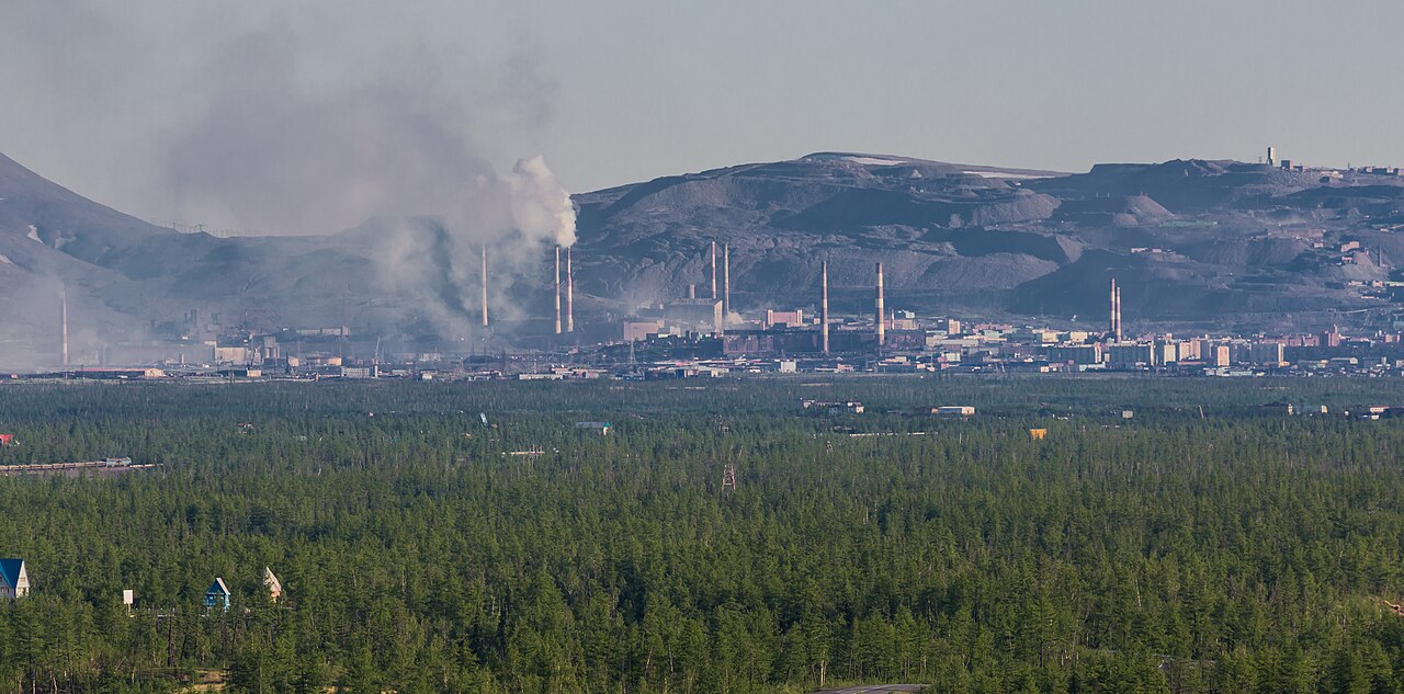 Norilsk in winter, industrial stacks beyond snow and low buildings.